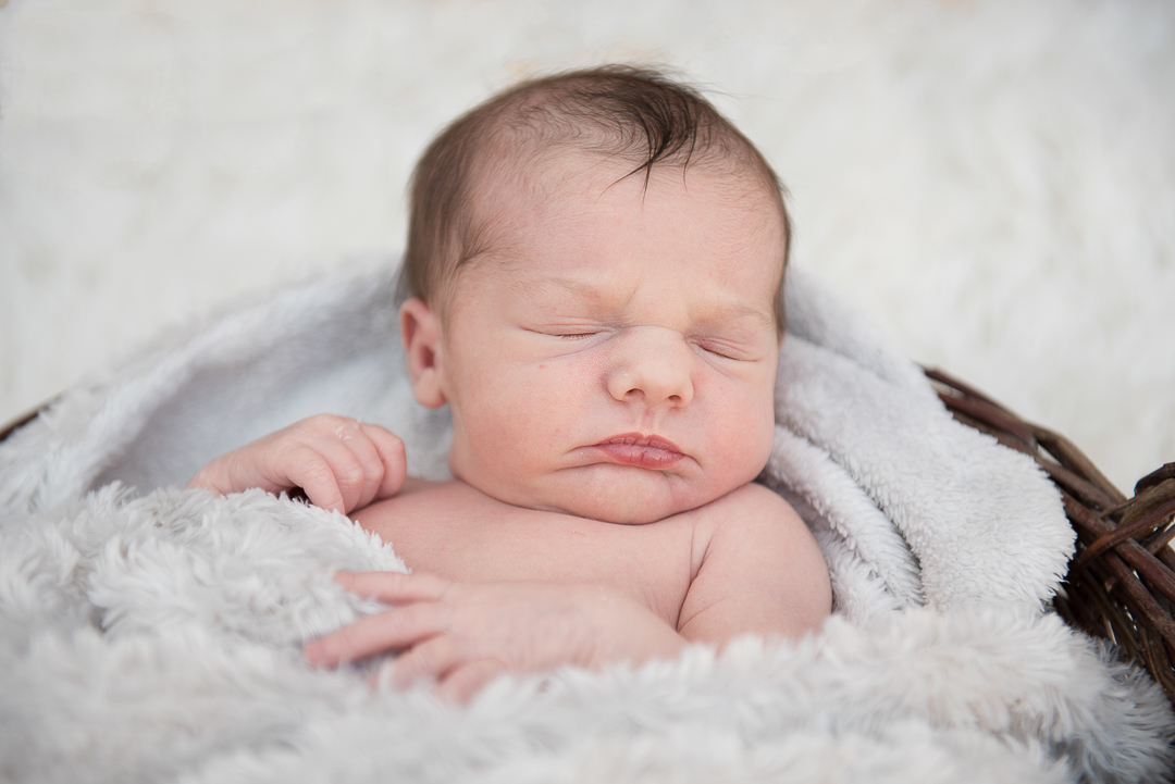 newborn baby with dark hair asleep in basket during newborn photography session in norfolk