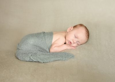 newborn baby in green wrap laying on tummy during newborn portrait session in norfolk by Alison Armstrong