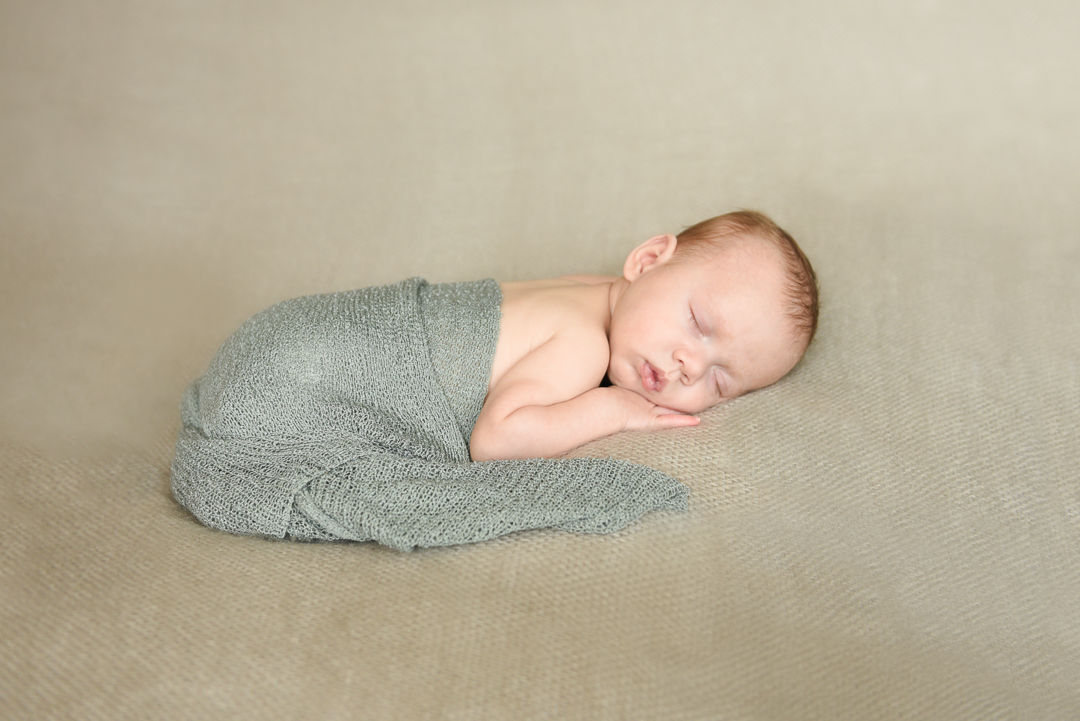 newborn baby in green wrap laying on tummy during newborn portrait session in norfolk by Alison Armstrong