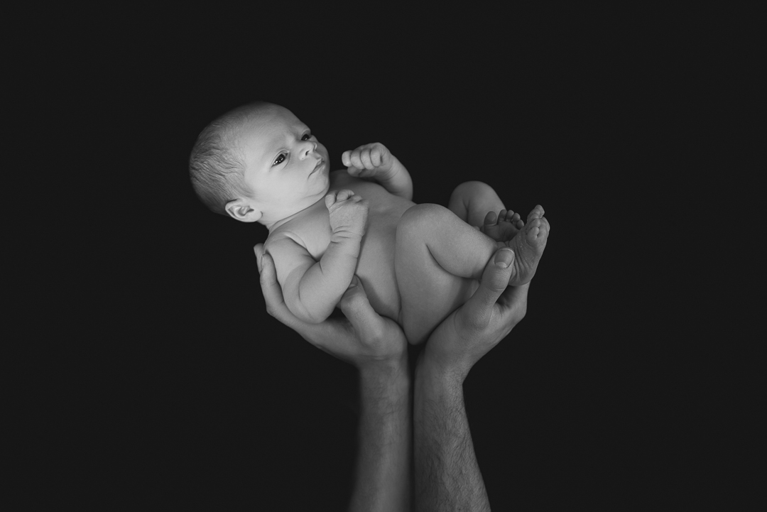 portrait of awake newborn baby in father's arms during photography session in norfolk