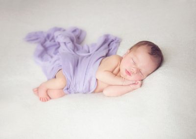 baby in purple blanket sleeping peacefully during newborn portrait session with Alison Armstrong