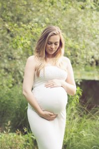 beautiful mum to be cradling bump during outdoor photography session in norfolk