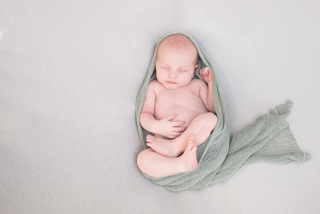 baby sleeping on back with green wrap during newborn session in norfolk