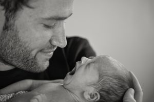 newborn baby yawning whilst dad smiles during at home norfolk photography session