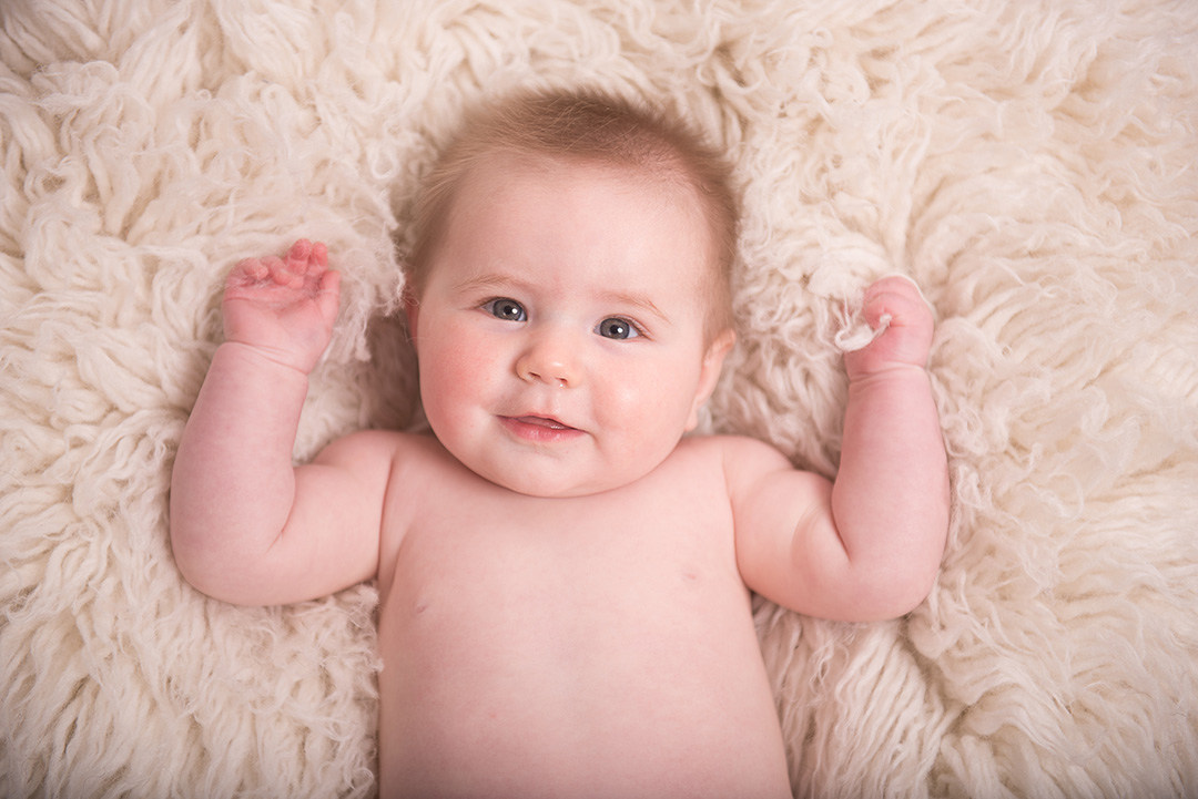 Baby laying on soft rug during baby portrait session in norfolk