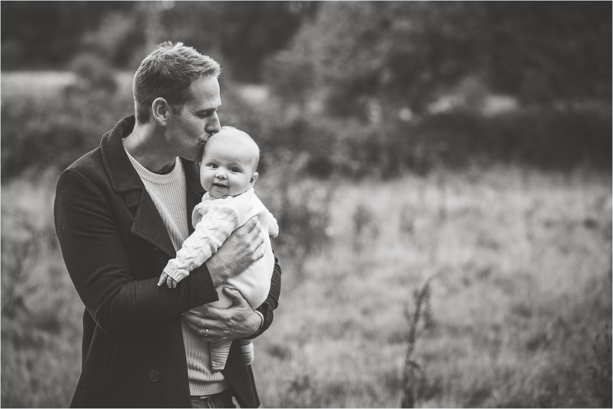 dad kissing baby on head during outdoor family portrait session