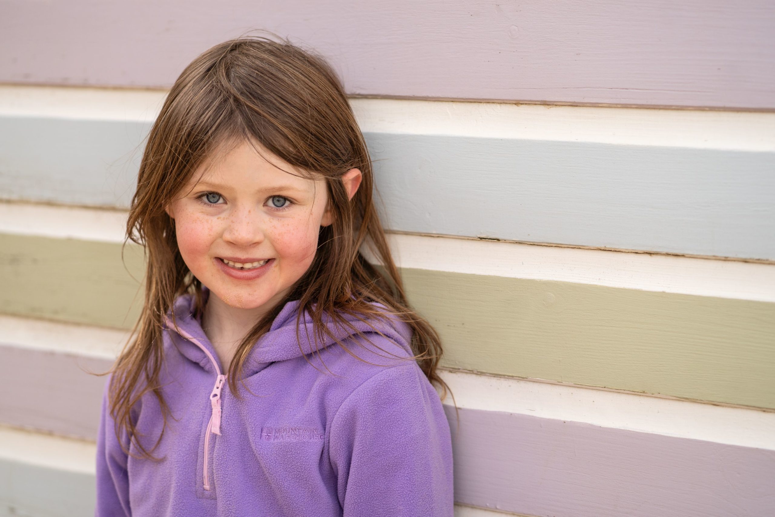 girl by beach hut in Norfolk beach family session