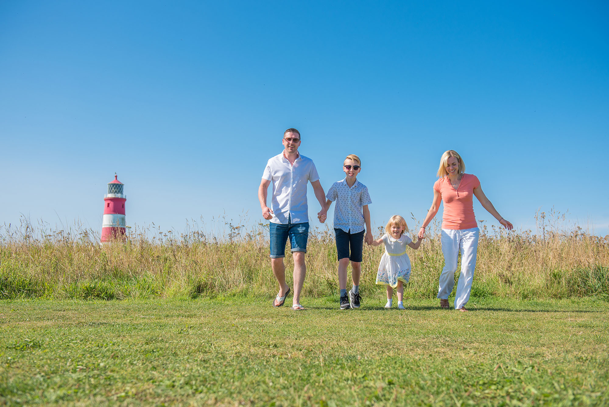 family holding hands at Happisburgh lighthouse during outdoor family photography session in Norfolk