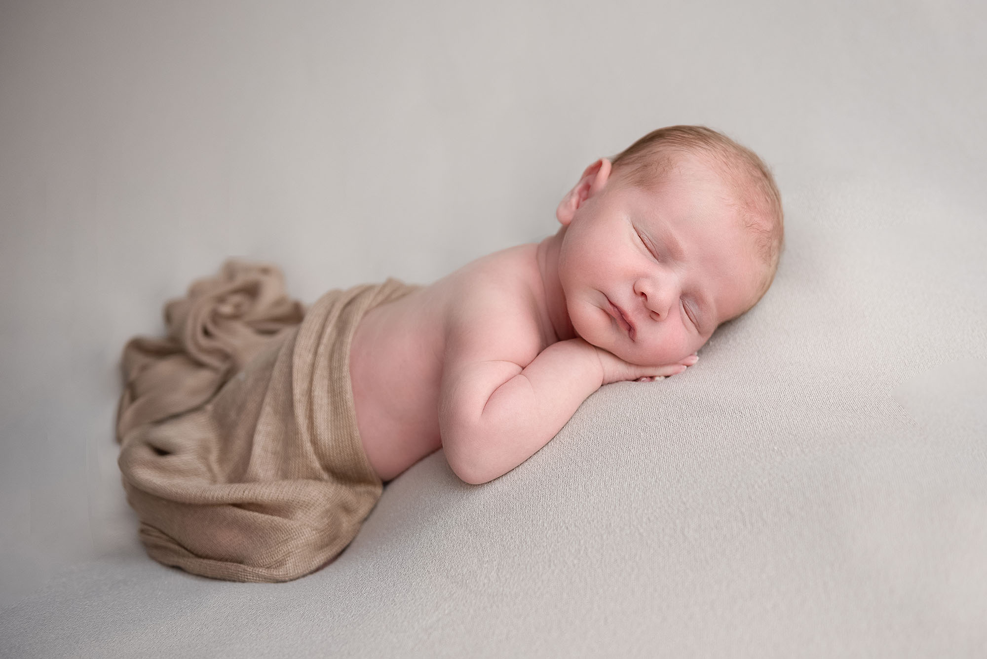 Sleeping newborn baby with brown wrap during newborn portrait session with Alison Armstrong